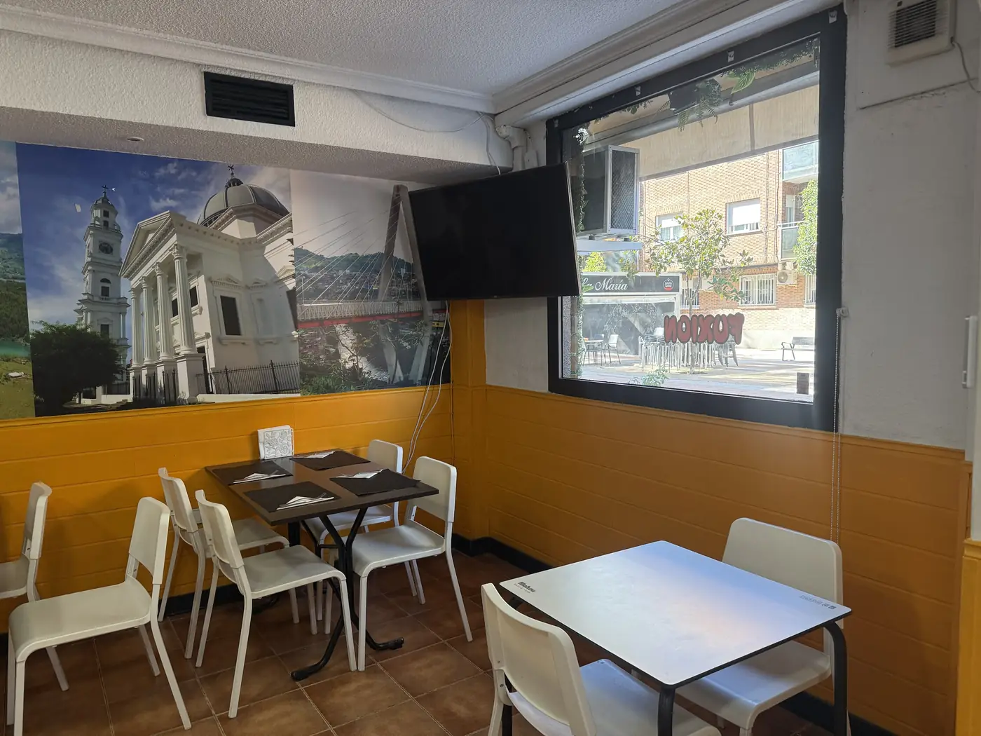 Comedor con mesas, paredes amarillas y grandes murales