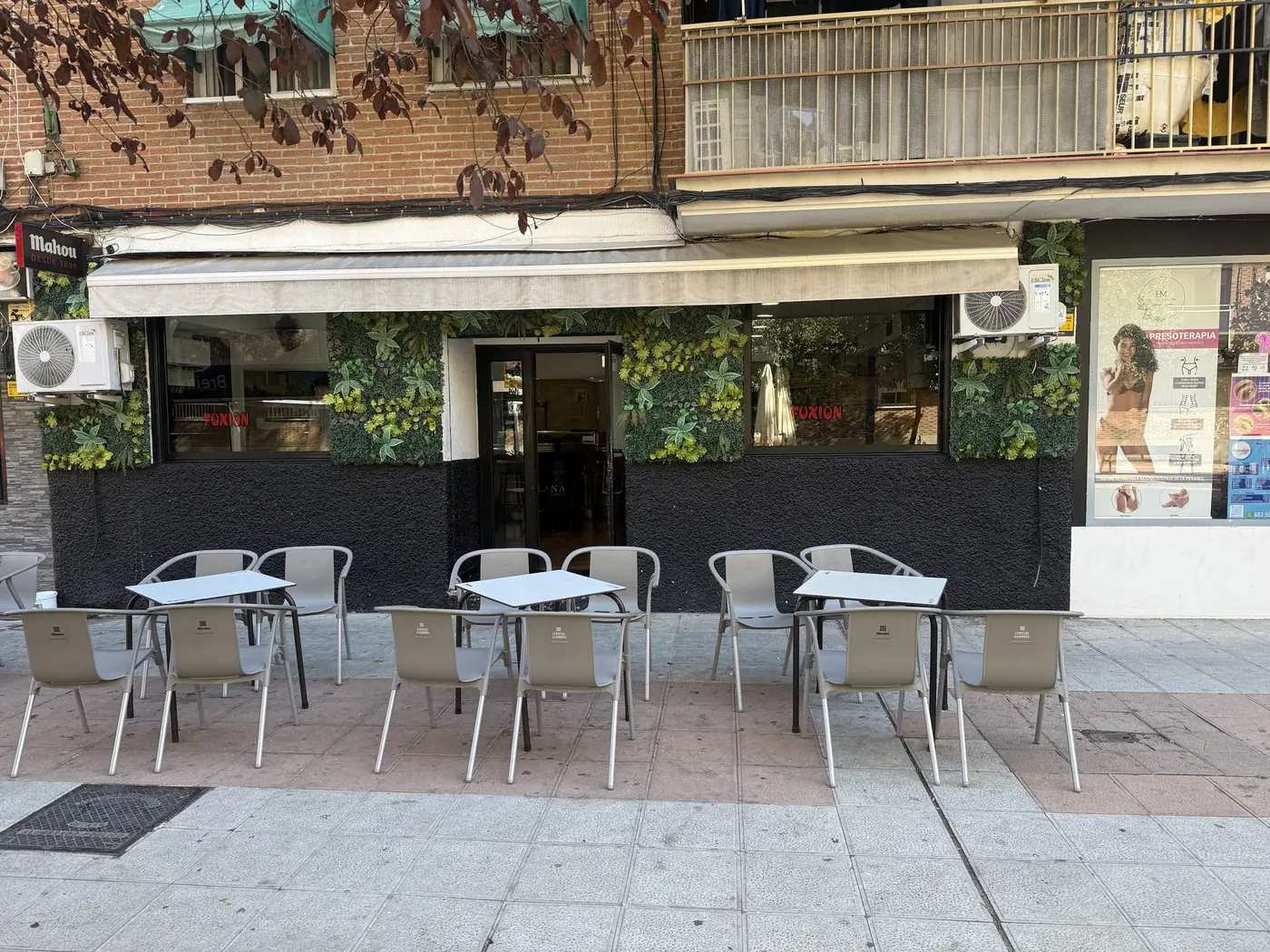 Terraza de Taberna Fuxión con mesas en el paseo, frente a la fachada con plantas